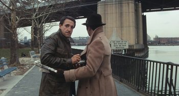 Movie still from “The Seven-Ups” (1973), directed by Philip D'Antoni – Two men in coats and a hat on a bridge; Medium shot, High angle