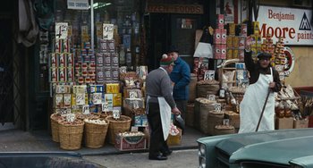 Movie still from “The Seven-Ups” (1973), directed by Philip D'Antoni – Two men standing in front of a store with baskets of nuts; Wide shot, High angle