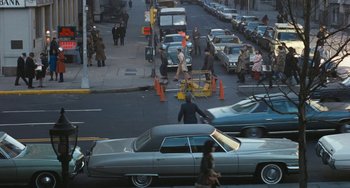 Movie still from “The Seven-Ups” (1973), directed by Philip D'Antoni – A street scene with cars and people walking on the sidewalk; Extreme Wide shot, High angle