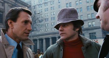 Movie still from “The Seven-Ups” (1973), directed by Philip D'Antoni – A man wearing a hat talking to another man in a crowd; Close Up shot, Low angle