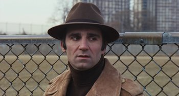 Movie still from “The Seven-Ups” (1973), directed by Philip D'Antoni – A man wearing a brown hat and a brown jacket; Close Up shot, Over the shoulder angle