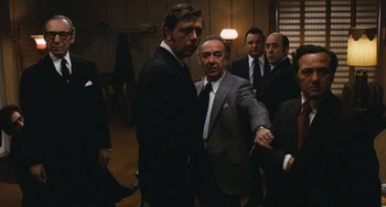 Movie still from “The Seven-Ups” (1973), directed by Philip D'Antoni – A group of men standing around each other in a room; Medium shot, Over the shoulder angle