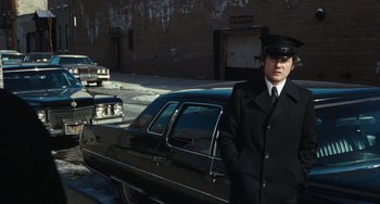 Movie still from “The Seven-Ups” (1973), directed by Philip D'Antoni – A man standing in front of an old car; Medium shot, Over the shoulder angle