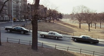 Movie still from “The Seven-Ups” (1973), directed by Philip D'Antoni – Cars driving down a street near a tree; Extreme Wide shot, High angle