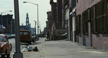 Movie still from “The Seven-Ups” (1973), directed by Philip D'Antoni – A street scene with a man walking down the sidewalk; Extreme Wide shot, High angle
