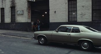 Movie still from “The Seven-Ups” (1973), directed by Philip D'Antoni – An old car parked in front of a building; Wide shot, High angle
