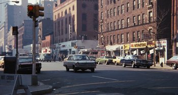 Movie still from “The Seven-Ups” (1973), directed by Philip D'Antoni – A car is driving down a busy city street; Extreme Wide shot, High angle