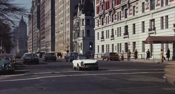 Movie still from “The Seven-Ups” (1973), directed by Philip D'Antoni – A white car driving down a street next to tall buildings; Extreme Wide shot, High angle
