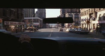 Movie still from “The Seven-Ups” (1973), directed by Philip D'Antoni – A view from inside a car looking out the window at a busy city street; Wide shot, Over the shoulder angle