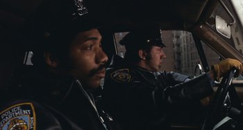 Movie still from “The Seven-Ups” (1973), directed by Philip D'Antoni – Two police officers sitting in the back of a car; Close Up shot, Low angle