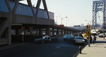 Movie still from “The Seven-Ups” (1973), directed by Philip D'Antoni – A police car driving down a street next to an overpass; Extreme Wide shot, High angle