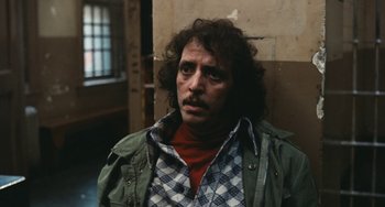 Movie still from “The Seven-Ups” (1973), directed by Philip D'Antoni – A man in a plaid shirt and a green jacket looking to his left; Close Up shot, Over the shoulder angle