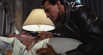 Movie still from “The Seven-Ups” (1973), directed by Philip D'Antoni – A man is holding a man's hand while he is lying on a bed; Medium shot, High angle
