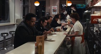 Movie still from “The Seven-Ups” (1973), directed by Philip D'Antoni – A group of people sitting at a counter in a restaurant; Wide shot, High angle