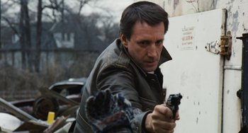 Movie still from “The Seven-Ups” (1973), directed by Philip D'Antoni – A man holding a gun while standing next to a wall; Close Up shot, Low angle