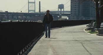 Movie still from “The Seven-Ups” (1973), directed by Philip D'Antoni – A man is walking on a sidewalk near a bridge; Wide shot, High angle