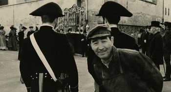 Movie still from “The Ship Sails On” (1983), directed by Federico Fellini – A black and white photo of a man and two men in hats; Medium shot, Over the shoulder angle