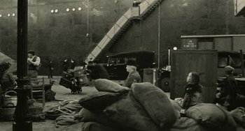 Movie still from “The Ship Sails On” (1983), directed by Federico Fellini – An old photo of a man sitting on a couch next to a car; Extreme Wide shot, High angle
