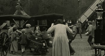 Movie still from “The Ship Sails On” (1983), directed by Federico Fellini – A group of people standing around a car; Wide shot, High angle