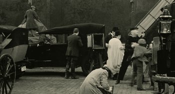 Movie still from “The Ship Sails On” (1983), directed by Federico Fellini – A group of people standing around a car; Wide shot, High angle