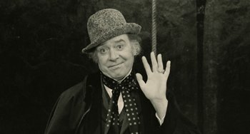 Movie still from “The Ship Sails On” (1983), directed by Federico Fellini – An older man wearing a hat and holding a rope; Close Up shot, Low angle