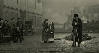 Movie still from “The Ship Sails On” (1983), directed by Federico Fellini – Two women and a girl standing on a cobblestone street; Wide shot, High angle