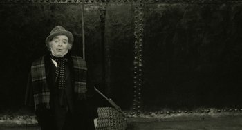 Movie still from “The Ship Sails On” (1983), directed by Federico Fellini – An old man standing in front of a wall; Medium shot, Low angle