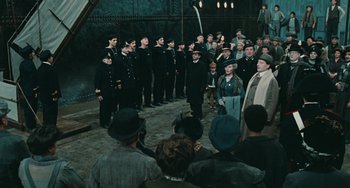 Movie still from “The Ship Sails On” (1983), directed by Federico Fellini – A group of men in uniform standing in front of a crowd; Wide shot, High angle