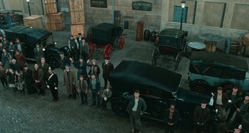 Movie still from “The Ship Sails On” (1983), directed by Federico Fellini – A group of people standing around a car; Extreme Wide shot, High angle