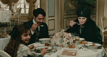 Movie still from “The Ship Sails On” (1983), directed by Federico Fellini – A group of people sitting at a table eating food; Medium shot, High angle
