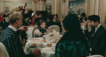 Movie still from “The Ship Sails On” (1983), directed by Federico Fellini – A group of people sitting around a table eating food; Wide shot, High angle