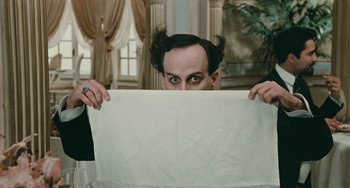 Movie still from “The Ship Sails On” (1983), directed by Federico Fellini – A man in a black shirt is hiding behind a white sheet; Close Up shot, Overhead angle