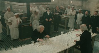 Movie still from “The Ship Sails On” (1983), directed by Federico Fellini – A group of people standing around a long table; Wide shot, High angle