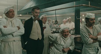 Movie still from “The Ship Sails On” (1983), directed by Federico Fellini – A group of people in a kitchen wearing chef's hats and aprons; Medium shot, High angle