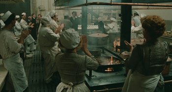 Movie still from “The Ship Sails On” (1983), directed by Federico Fellini – A group of people standing in a kitchen cooking food; Wide shot, High angle