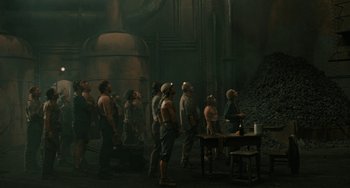 Movie still from “The Ship Sails On” (1983), directed by Federico Fellini – A group of men standing in front of a pile of coal; Wide shot, High angle