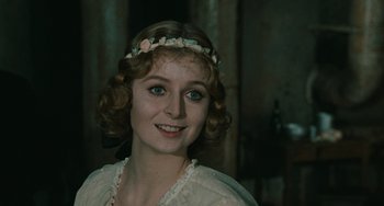 Movie still from “The Ship Sails On” (1983), directed by Federico Fellini – A young woman wearing a flower crown and smiling; Close Up shot, Over the shoulder angle