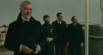 Movie still from “The Ship Sails On” (1983), directed by Federico Fellini – A group of men standing next to each other in suits; Medium shot, Low angle