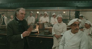 Movie still from “The Ship Sails On” (1983), directed by Federico Fellini – A group of people wearing chef's hats in a kitchen; Medium shot, Over the shoulder angle