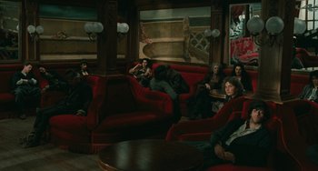 Movie still from “The Ship Sails On” (1983), directed by Federico Fellini – A group of people sitting on a red couch in a living room; Wide shot, High angle