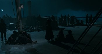 Movie still from “The Ship Sails On” (1983), directed by Federico Fellini – A group of people sitting on the ground at night; Extreme Wide shot, High angle