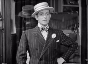 Movie still from “The Shop Around the Corner” (1940), directed by Ernst Lubitsch – A man wearing a suit and hat posing for a picture; Medium shot, High angle