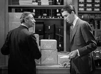 Movie still from “The Shop Around the Corner” (1940), directed by Ernst Lubitsch – Two men in business suits are talking in a room; Medium shot, High angle