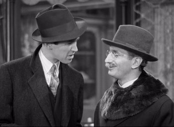 Movie still from “The Shop Around the Corner” (1940), directed by Ernst Lubitsch – A man and a man wearing a hat and a tie; Medium shot, Over the shoulder angle
