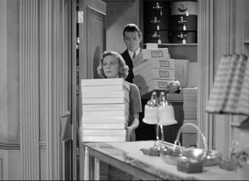 Movie still from “The Shop Around the Corner” (1940), directed by Ernst Lubitsch – A man and a woman holding boxes in a room; Medium shot, Low angle