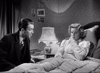 Movie still from “The Shop Around the Corner” (1940), directed by Ernst Lubitsch – A man and a woman sitting on a bed in front of a lamp; Medium shot, Overhead angle