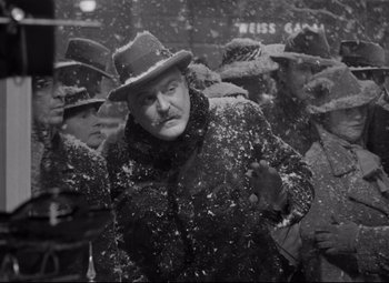 Movie still from “The Shop Around the Corner” (1940), directed by Ernst Lubitsch – A man in a hat and a coat standing in the snow; Medium shot, High angle