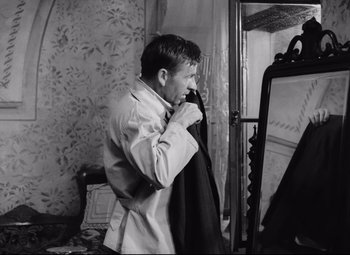 Movie still from “The Shop on Main Street” (1965), directed by Ján Kadár – A black and white photo of a man holding a suit jacket; Medium shot, Over the shoulder angle