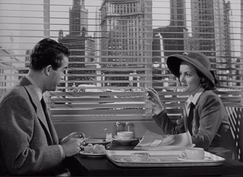 Movie still from “The Snake Pit” (1948), directed by Anatole Litvak – A man and a woman sitting at a table in front of a city skyline; Medium shot, High angle
