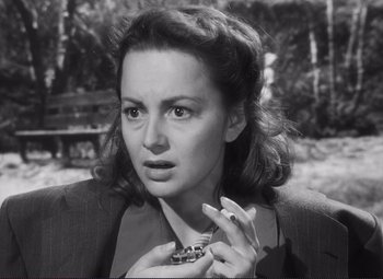 Movie still from “The Snake Pit” (1948), directed by Anatole Litvak – An old black and white photo of a woman holding a cigarette; Close Up shot, High angle